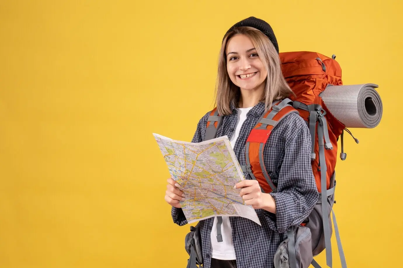 지도를 들고 배낭을 멘 행복한 여성 여행자의 정면 모습